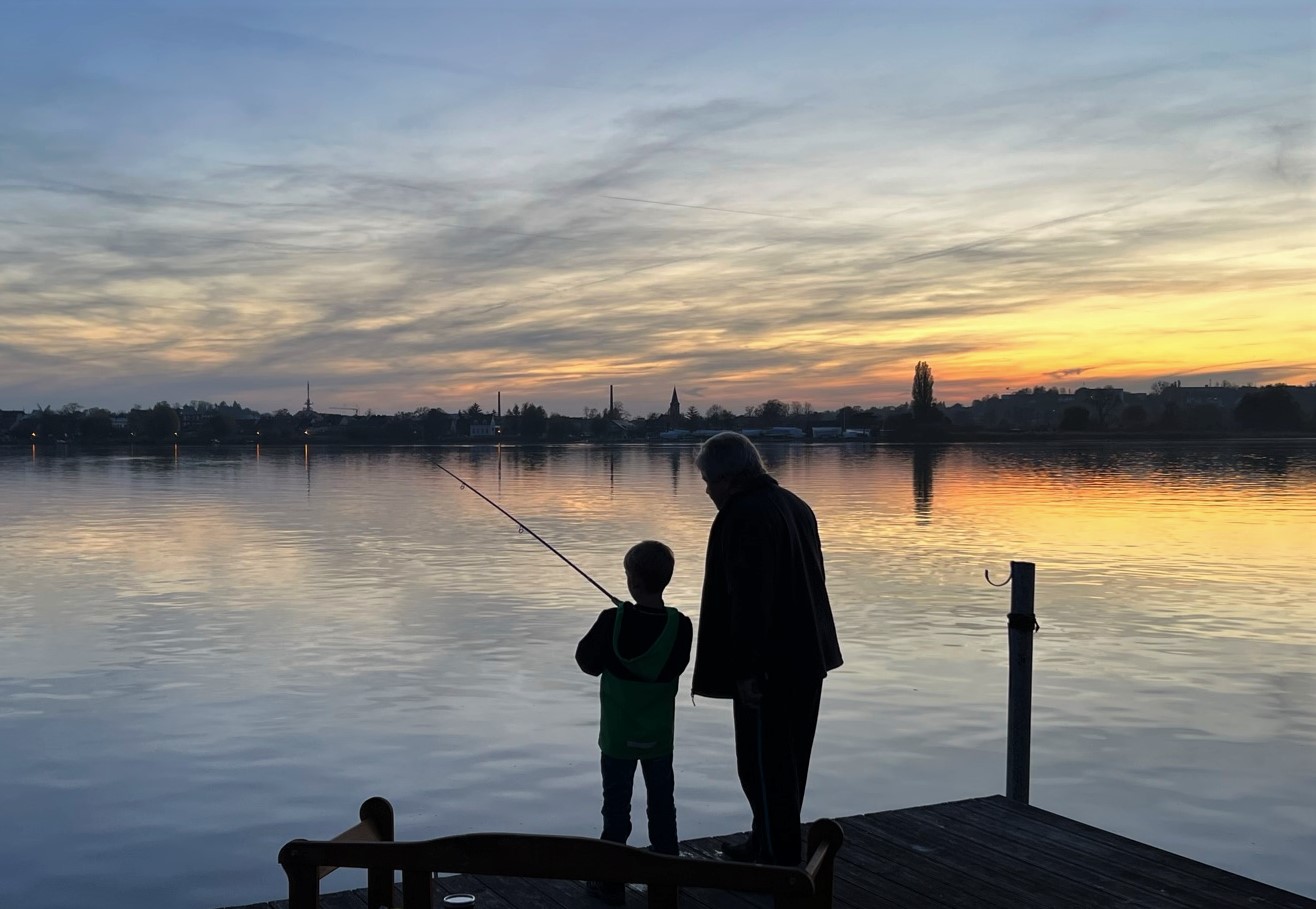 Opa und Enkel beim Angeln im Sonnenuntergang